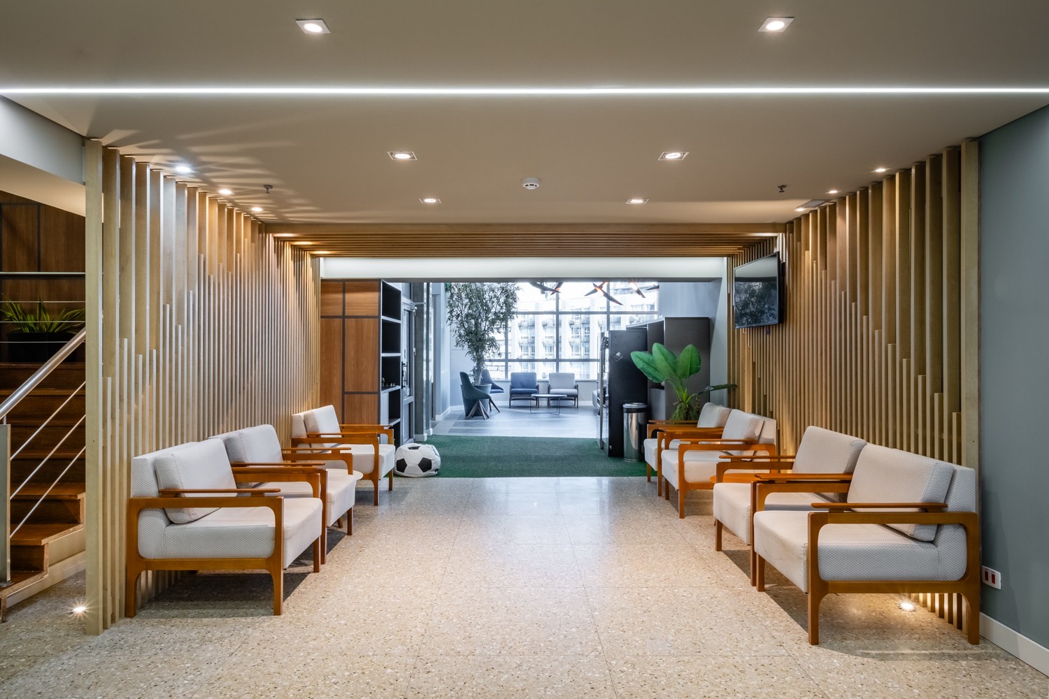 Recepção da unidade Paulista, com poltronas claras, painéis de madeira e luz natural ao fundo